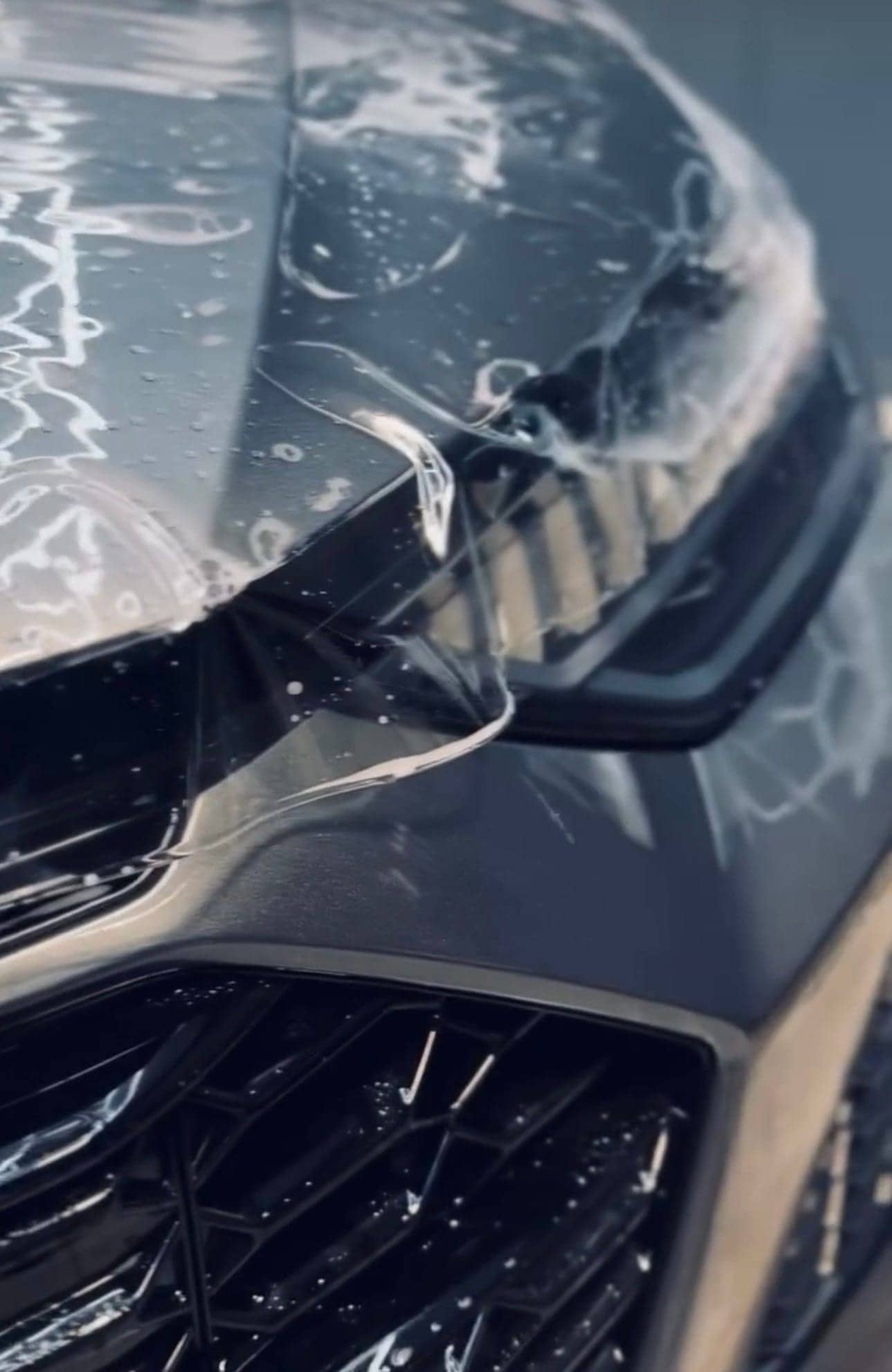 Close-up of clear film being laid over a headlight during an install
